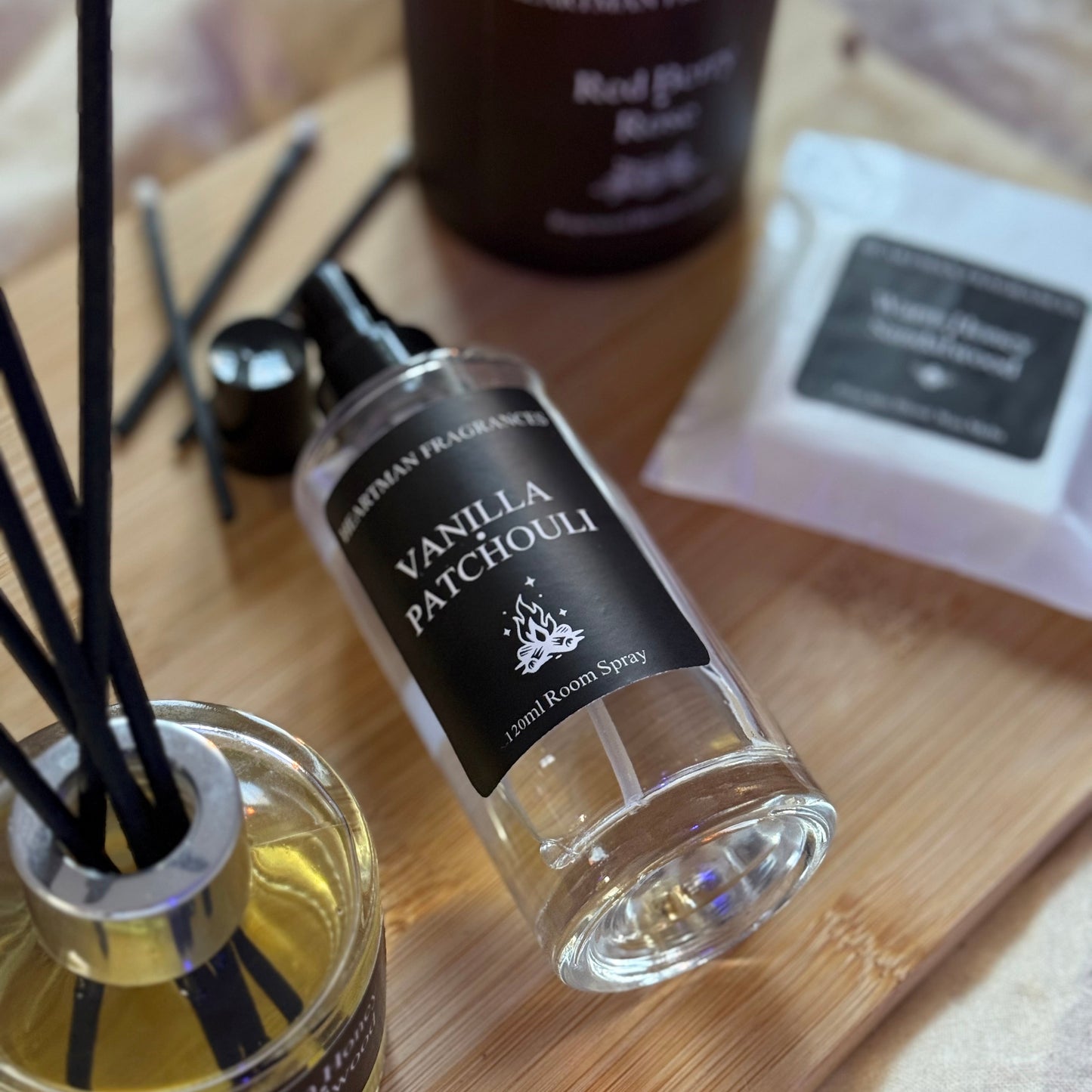 Vanilla Patchouli diffuser bottle on a wooden surface with other home fragrance items.
