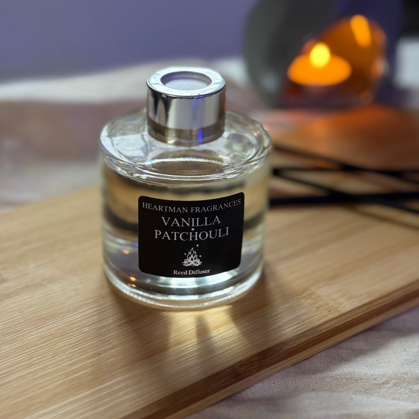 Vanilla Patchouli reed diffuser bottle on a wooden surface with a blurred background