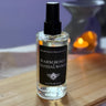 Bottle of Warm Honey Sandalwood room spray on a wooden surface with a blurred background