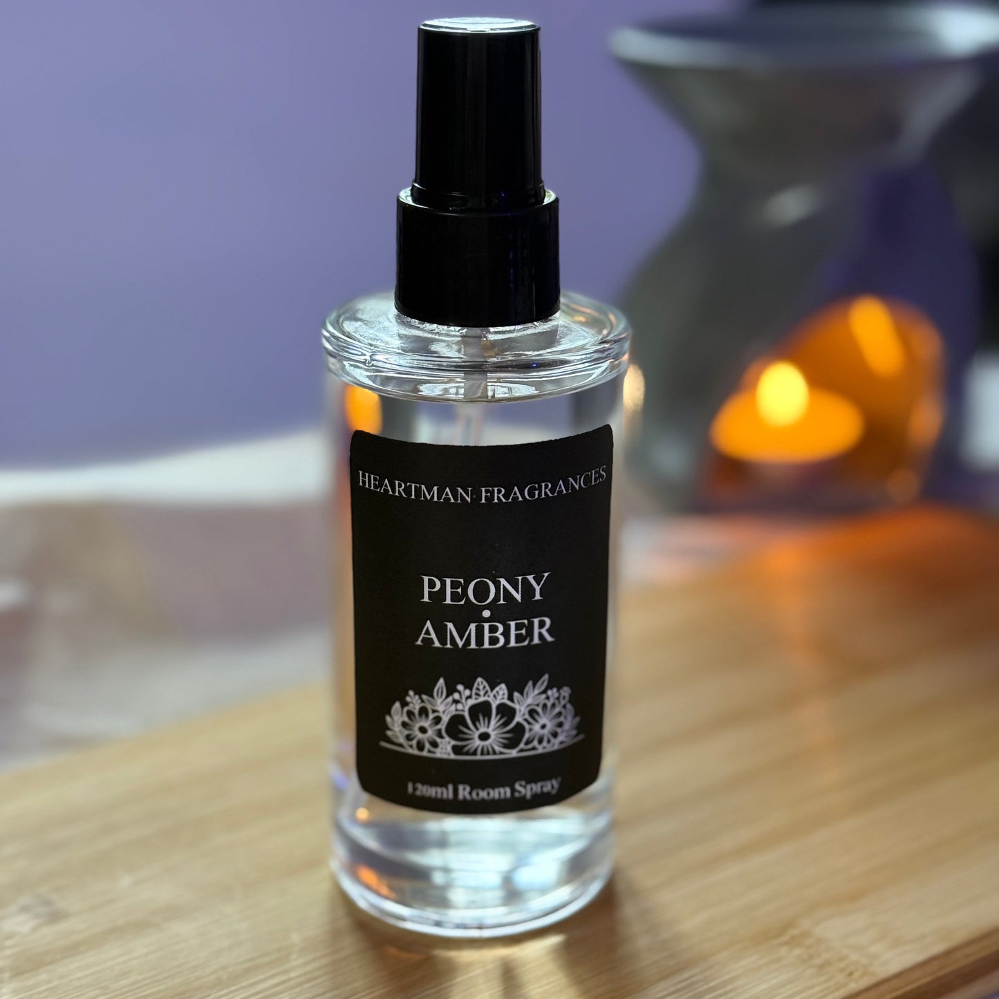 Peony Amber room spray bottle on a wooden surface with a blurred background